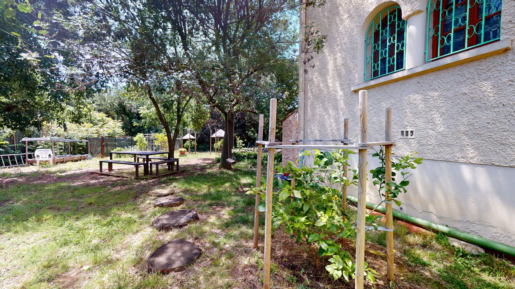Le jardin arboré, la table de pique-nique et les fenêtres aux grilles turquoise